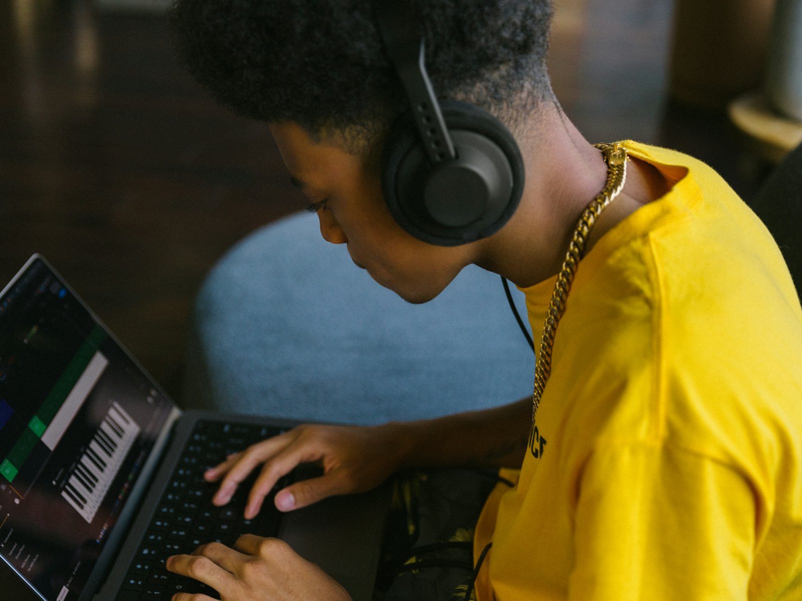 Junger Produzent mit Kopfhörern am Laptop